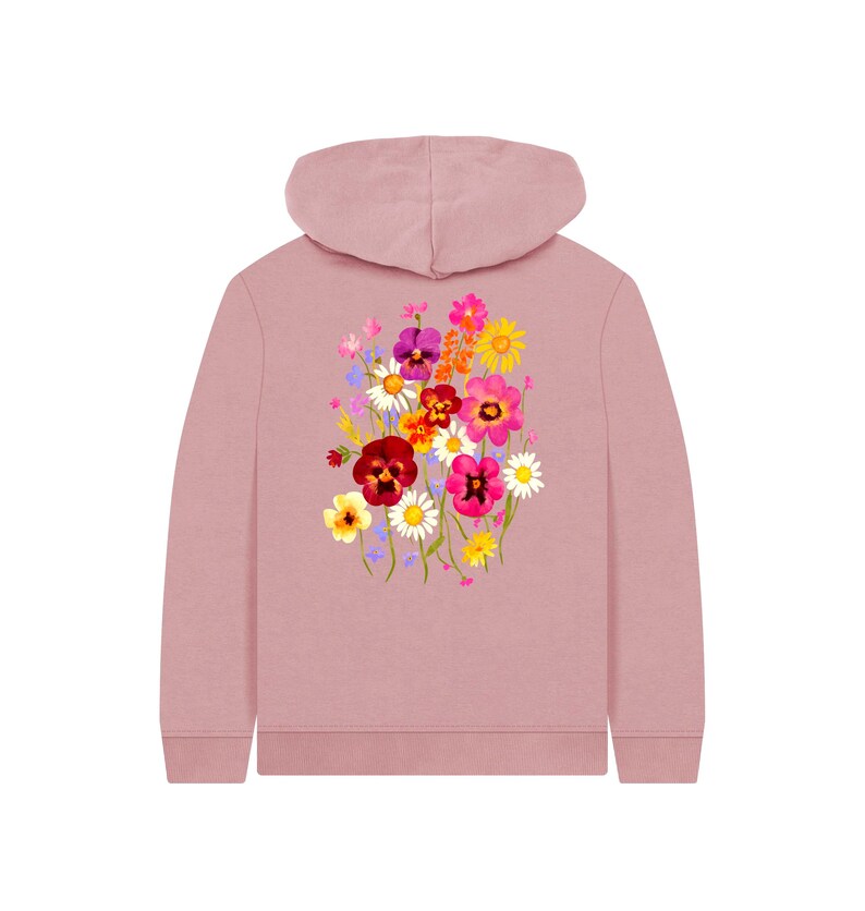 May include: A dusty rose hoodie featuring a vibrant floral design on the back. The colorful bouquet includes pansies, daisies, and other wildflowers in shades of pink, yellow, red, and purple. The hoodie has a hood and long sleeves.