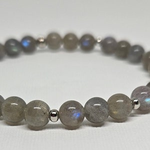 Può includere: Un braccialetto in pietra di labradorite grigia con perline d'argento.