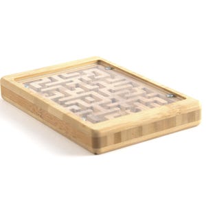 May include: A wooden maze puzzle with a clear plastic top. The maze is made of light brown wood and features a complex path for a small metal ball to navigate. The frame is rectangular and made of bamboo.