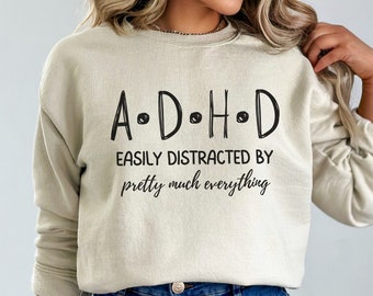 May include: A beige sweatshirt with black text that reads "A.D.H.D. Easily Distracted By pretty much everything."