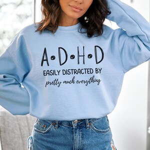 May include: Light blue sweatshirt with the text "A.D.H.D. Easily Distracted By pretty much everything" printed on the front.