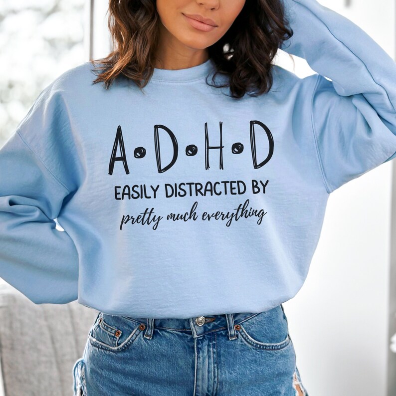 May include: Light blue sweatshirt with the text "A.D.H.D. Easily Distracted By pretty much everything" printed on the front.