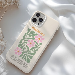 May include: A cream-colored phone case featuring a floral design with pink flowers and green leaves. The text "PSALM 37:4" is printed in orange, along with a quote. The case is designed to fit a smartphone and has a camera cutout.