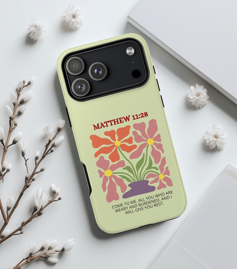 May include: A light green phone case featuring a floral design with orange and pink flowers in a purple vase. The text "MATTHEW 11:28" is above the flowers, and the quote "COME TO ME, ALL YOU WHO ARE WEARY AND BURDENED, AND I WILL GIVE YOU REST" is below.
