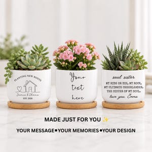 May include: Three white ceramic planters with bamboo saucers, each containing different plants. The left planter features a house line drawing and text "PLANTING NEW ROOTS Jamie & Shane EST. 2026". The center says "Your text here". The right says "soul sister" with a message.