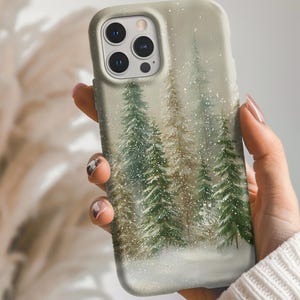May include: A phone case featuring a winter forest scene with snow-covered evergreen trees. The case has a light beige background and a glossy finish. The design includes shades of green, brown, and white, creating a serene, nature-inspired aesthetic.