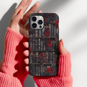 May include: A black phone case with a design of a bookshelf filled with books and red roses.