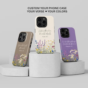 May include: Three custom phone cases with floral designs and inspirational quotes. One case is tan with the text "You are the light of the world", another is off-white with "God is within her, she will not fall", and the third is purple with "I can do all things through Christ".