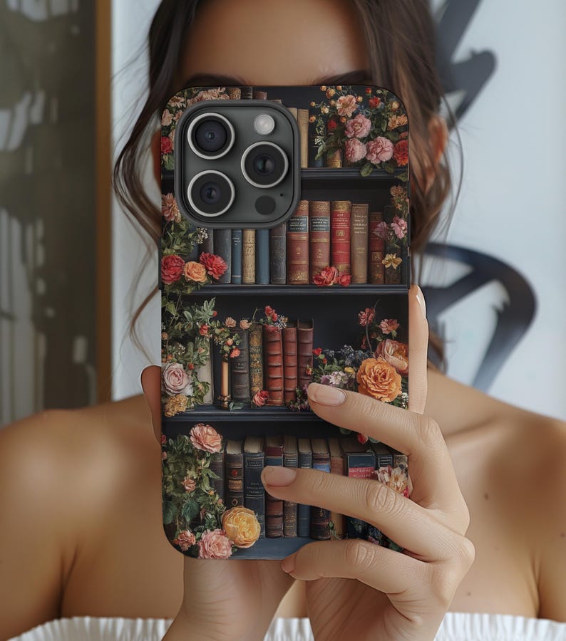 Puede incluir: Una funda de tel&eacute;fono negra con un dise&ntilde;o floral y una estanter&iacute;a llena de libros. La funda tiene una lente de c&aacute;mara con tres lentes.