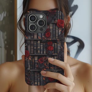 May include: A black phone case with a bookshelf design featuring red roses and vintage books. The case has a camera lens cutout.