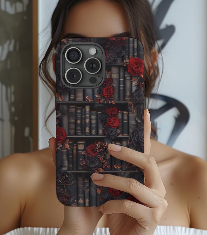 May include: A black phone case with a bookshelf design featuring red roses and vintage books. The case has a camera lens cutout.