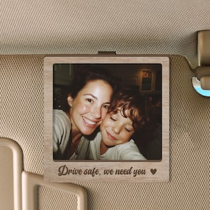 May include: A square wooden photo frame with a light brown grain finish, featuring a photograph of an adult and a child smiling together. The bottom border of the frame is engraved with the text "Drive safe, we need you" and a small heart symbol.