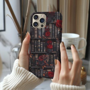 May include: A black phone case with a design of a bookshelf filled with books and red roses.