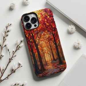 May include: A phone case featuring a vibrant autumn forest scene. The design showcases a mosaic-like depiction of trees with red, orange, and yellow leaves. The case has a black border and a camera cutout.