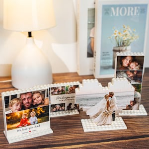 May include: White brick-style photo frames displaying family photos. One frame reads "We love you dad" with names below. Another shows a couple kissing. A magazine and lamp are in the background.