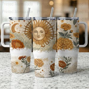 Puede incluir: Tres vasos de acero inoxidable con fondo blanco y un diseño de sol, luna y flores. Los vasos tienen una tapa blanca y una pajita.