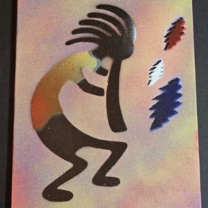 Könnte beinhalten: Ein kleines Leinwandgemälde mit einer stilisierten Kokopelli-Figur in Braun, mit einem gelb-orangen Torso, der eine Flöte spielt. Drei farbige, stilisierte Federn in Rot, Weiß und Blau befinden sich rechts. Der Hintergrund ist eine Mischung aus Rosa, Gelb und Orange.