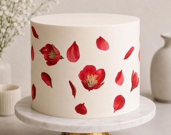 May include: A cylindrical cake with smooth off-white frosting decorated with scattered vibrant red flower blossoms and individual petals. The cake sits on a white marble cake stand with a gold-colored metal base, showcasing a clean design.