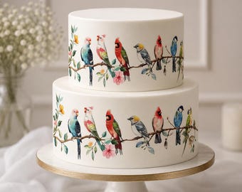 May include: Two-tiered white cake decorated with colorful bird illustrations perched on branches with flowers. The cake sits on a white and gold cake stand. The cake is a dessert for a special occasion.