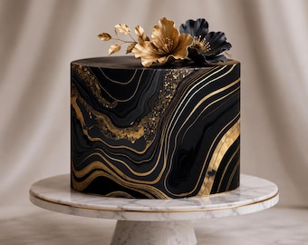 May include: A cylindrical cake with a black surface featuring swirling gold marbled patterns and gold glitter accents. The top is decorated with one metallic gold flower and one black flower with gold centers, all resting on a white marble cake stand.