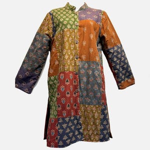 May include: A long patchwork coat with a mandarin collar and long sleeves. The coat features a variety of patterned fabric squares in shades of green, orange, red, blue, and purple. It has wooden buttons down the front and side slits.