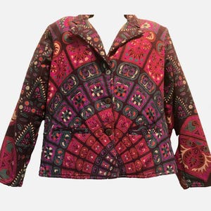 May include: A patterned blazer in shades of pink, purple, and brown. The jacket features a button-up front, notched lapels, and two front pockets. The fabric has a geometric design with floral and paisley elements.
