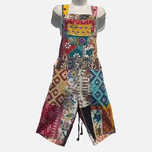 May include: A pair of overalls featuring a patchwork design with various colorful patterns including floral, paisley, geometric, and animal motifs in shades of red, yellow, blue, and white. The garment has a square neckline and shoulder straps.