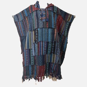 May include: A hooded poncho constructed from a patchwork of woven fabric panels in shades of blue, red, and dark green. The garment features vertical stripes, geometric patterns, a front placket with toggle closures, and a fringed bottom hem.