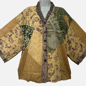 May include: A patchwork kimono-style jacket featuring a mix of yellow, olive green, and black patterns. The garment includes floral prints, a dotted texture, and a snake-skin pattern along the collar and front placket with five dark buttons.