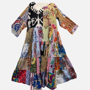 May include: A patchwork dress featuring a variety of colorful fabric patterns. The dress has a round neckline and long sleeves. The design incorporates floral, geometric, and abstract prints in a tiered, flowing silhouette.