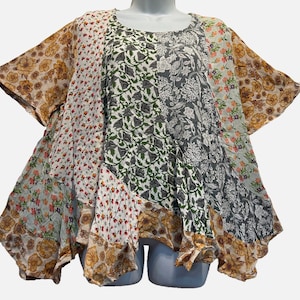 May include: A short-sleeved tunic top featuring a patchwork design of various floral and botanical patterns in shades of mustard yellow, white, dark green, and charcoal gray. The garment has a round neckline and an asymmetrical, flared hemline.