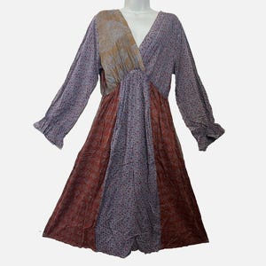 May include: A long-sleeved dress featuring a V-neckline and a patchwork design. The garment combines panels of light purple fabric with small floral patterns, a solid mustard-colored section at the chest, and deep rust-colored floral patterned panels.