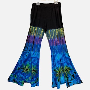 May include: High-waisted flared pants featuring a solid black waistband and upper section that transitions into a vibrant tie-dye pattern. The lower legs display a gradient of yellow, purple, and blue hues with distinct starburst motifs.