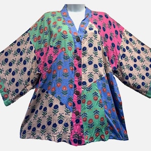 May include: A patchwork kimono-style top with a V-neck and button closure. The top features a variety of floral patterns in shades of pink, blue, green, and beige. The sleeves are wide and the overall style is loose and flowing.