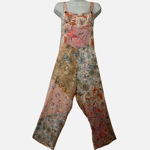 May include: A sleeveless jumpsuit featuring a patchwork design with various floral and botanical patterns in shades of rust orange, dusty pink, beige, and muted blue. The garment has wide shoulder straps, a square neckline, and wide-leg trousers.