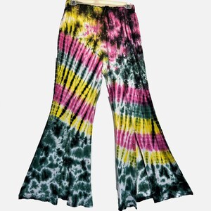 May include: Wide-leg pants featuring a vibrant tie-dye pattern in shades of yellow, hot pink, and dark forest green. The garment has an elasticized waistband with a drawstring and vertical slits along the lower outer seams of each leg.