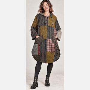 May include: A hooded tunic dress featuring a patchwork design with various textures and patterns in shades of olive green, charcoal gray, and muted red. The garment includes three-quarter length sleeves, two front pockets, and a button-up neckline.
