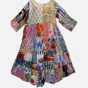 May include: A patchwork dress featuring a variety of colorful fabric patterns. The dress has a round neckline and three-quarter sleeves. The skirt is made of numerous squares of fabric in various colors and designs.