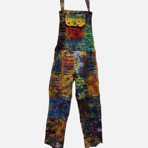 May include: Colorful patchwork overalls with adjustable straps and a front pocket. The garment features a variety of patterned fabric squares in shades of blue, yellow, red, and green. The overall design is casual and bohemian.