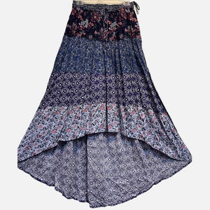 May include: A high-low skirt featuring a tiered design with a mix of navy blue, light blue, and white patterns. The top tier has a floral print, followed by a geometric pattern, and a lower floral section. It includes an elasticized drawstring waist.