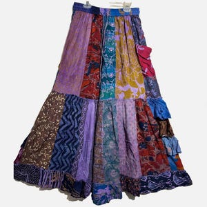May include: A patchwork skirt with a tiered design. The skirt features a variety of colorful fabrics in shades of purple, blue, red, and yellow. The skirt has an elastic waistband and a flowing, bohemian style.