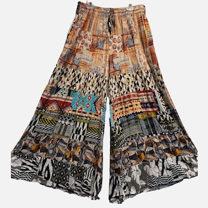 May include: Wide-leg pants featuring a tiered construction and a drawstring waist. The garment displays a multi-colored patchwork pattern with various geometric, tribal, and floral motifs in shades of orange, yellow, blue, black, and white.