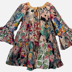 May include: A patchwork dress with a vibrant floral pattern. The dress features long sleeves with flared cuffs and a tiered skirt. The color palette includes pink, blue, green, and yellow, creating a bohemian aesthetic.