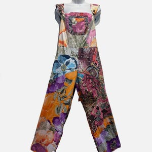 May include: A colorful jumpsuit with a patchwork design featuring floral and abstract patterns in shades of orange, purple, blue, and pink. The jumpsuit has a square neckline and wide legs, creating a bohemian style.