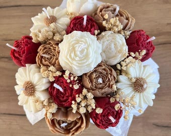 Puede incluir: Un ramo de flores de vela de color rojo, blanco y marrón. Las flores están dispuestas en una caja blanca y están rodeadas de flores secas.