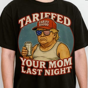 Könnte beinhalten: Schwarzes T-Shirt mit einer Cartoon-Illustration eines Mannes mit roter Kappe und Sonnenbrille mit amerikanischem Flaggen-Design, der eine Dose hält. Der Text auf dem Shirt lautet "Tariffed Tariff Daddy Your Mom Last Night."