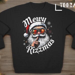 Könnte beinhalten: Schwarzer Pullover mit einer weißen Grafik von Weihnachtsmann mit Sonnenbrille und Weihnachtsmütze. Der Text "Mewy Rizzmas" steht unter dem Bild.
