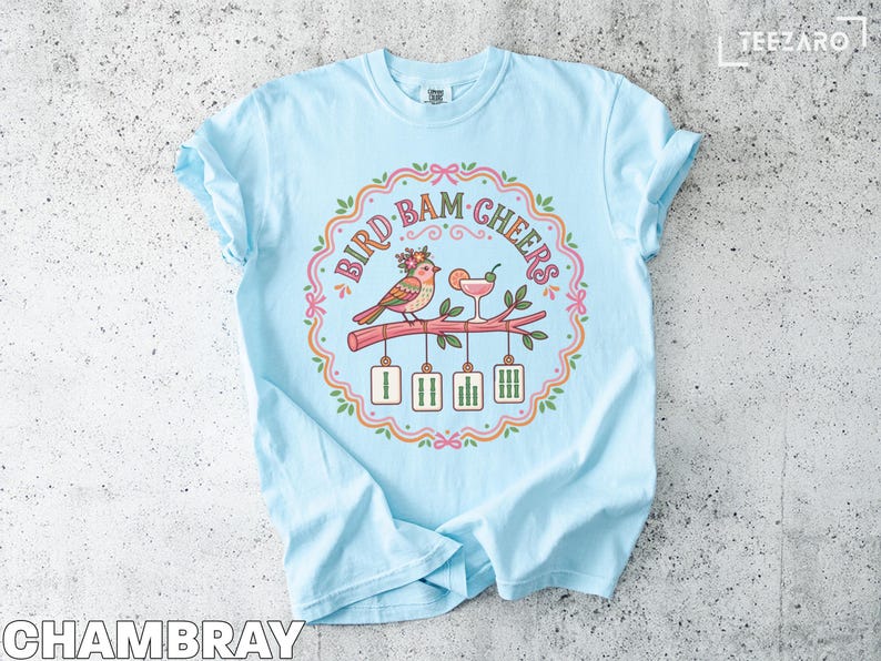Light blue t-shirt with "Bird, Bam, Cheers" text and illustration of birds with cocktails.