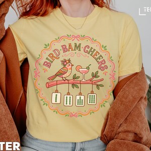 Yellow t-shirt with "Bird Bam Cheers" text and a bird on a branch.