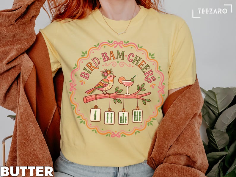 Yellow t-shirt with "Bird Bam Cheers" text and a bird on a branch.